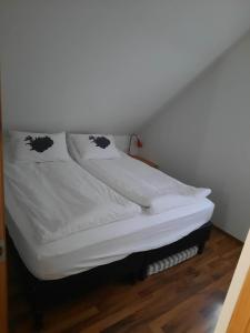 Una cama con sábanas blancas y almohadas. en Vinland Cottage en Egilsstadir