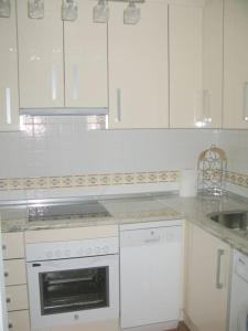 a white kitchen with a stove and a sink at La Fuente, apartment in the Moorish quarter. in Frigiliana