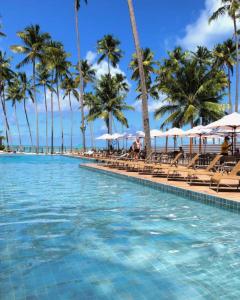 uma piscina na praia com palmeiras em Ipioca Beach Resort em Maceió