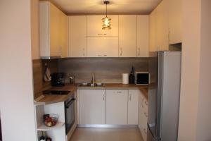 uma cozinha com armários brancos e um frigorífico de aço inoxidável em МОЯТ РАЙ - ПАДАЛОТО em Smolyan