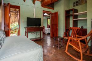 een slaapkamer met een bed, een bureau en een televisie bij Hacienda Puerta del Cielo Eco Lodge & Spa in Masaya