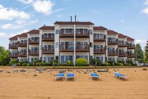 a large building on the beach with chairs and birds at Beachside 329 Waterfront Condo in Traverse City