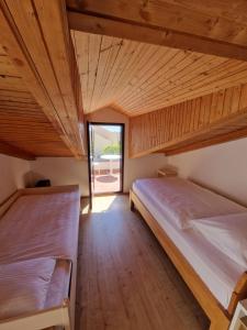 two beds in a room with wooden ceilings and a window at Apartments Dara in Rogoznica