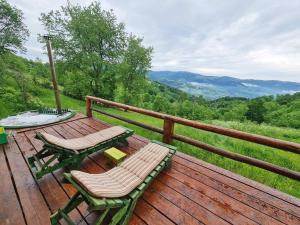 a wooden deck with two chairs and a table on it at Emoția Munților in Fericet