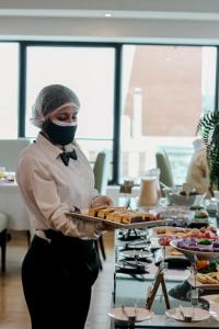 Una donna mascherata che tiene un vassoio di cibo di Hotel Miramar a Lima
