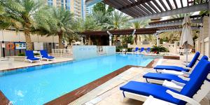 a swimming pool with blue lounge chairs in a hotel at HiGuests - Luxe Apartment With Incredible Marina Views in Dubai