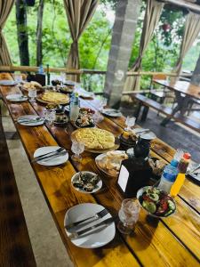 une longue table en bois avec des assiettes de nourriture dans l'établissement Martvili canyon cottage, à Gachedili