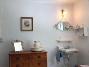 ein Badezimmer mit einem Waschbecken, einem Spiegel und einer Holzkommode in der Unterkunft VILLA EVA in Bray-Dunes