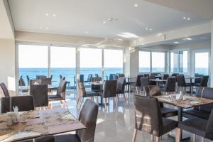 a restaurant with tables and chairs with the ocean in the background at Golden Coast Boutique - Luxury Living in Kypseli