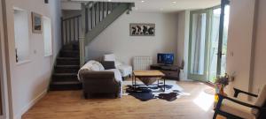 a living room with a staircase with a couch and a chair at The Workshop in Elham