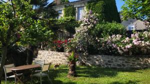 - un jardin avec une table, des chaises et des fleurs dans l'établissement Relais de la Renaissance, à Saint-Michel-de-Montaigne