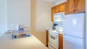 a kitchen with a white refrigerator and a sink at Fireside Lodge #315 By Bear Country in Sun Peaks