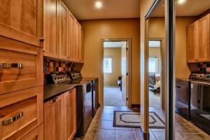 a kitchen with wooden cabinets and a hallway at Soleil Chalet By Bear Country in Sun Peaks