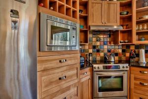 a kitchen with wooden cabinets and a microwave at Soleil Chalet By Bear Country in Sun Peaks