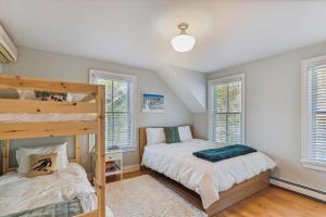 a bedroom with two bunk beds and two windows at Village Sunrise in Stowe