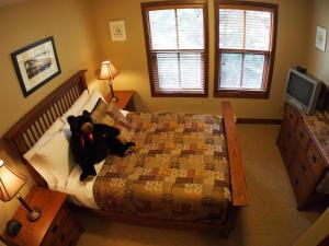 a teddy bear sitting on a bed in a bedroom at Woodhaven #16 By Bear Country in Sun Peaks