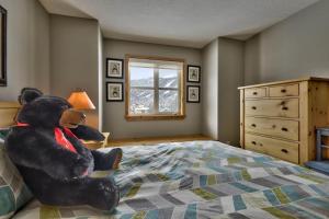 a teddy bear sitting on a bed in a bedroom at Crystal Forest #40 By Bear Country in Sun Peaks