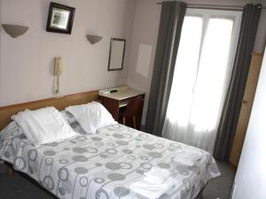 a bedroom with a bed and a desk and a window at Hotel Du Gave in Lourdes