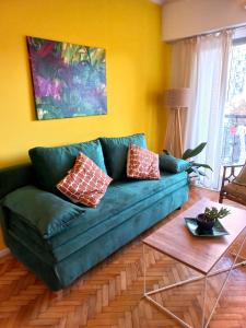 un sofá verde en una sala de estar con mesa en Boho style con balcón en Palermo Soho en Buenos Aires