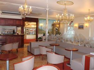 a restaurant with tables and chairs and chandeliers at Hotel Du Gave in Lourdes