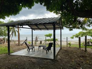 een paviljoen met 2 stoelen en een tafel op het strand bij Malibu beach in Punta de Piedra