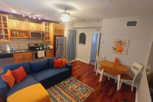 uma sala de estar com um sofá azul e uma cozinha em Itz a Vibe - 1 bedroom studio in the heart of DTSP em St. Petersburg
