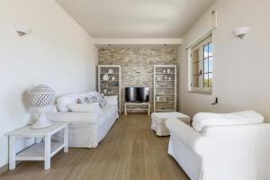 a living room with white furniture and a brick wall at L'Attico di Alessia by BarbarHouse in Maruggio