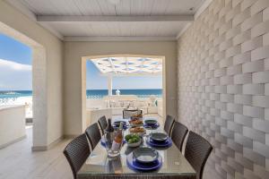 a dining room with a table and chairs and the ocean at L'Attico di Alessia by BarbarHouse in Maruggio