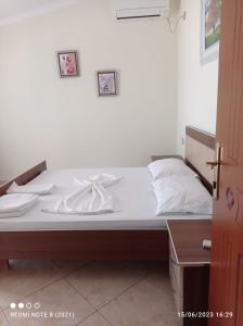 a bed with white sheets on it in a room at Guesthouse Fatos Biti in Divjakë