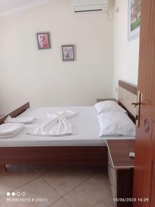 un letto con lenzuola bianche sopra in una stanza di Guesthouse Fatos Biti a Divjakë