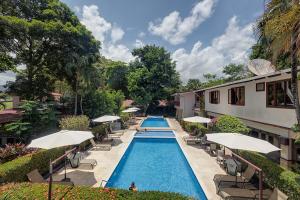 - une piscine avec des chaises et des parasols à côté d'un bâtiment dans l'établissement Hotel Mar de Luz, à Jacó