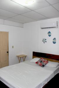 Schlafzimmer mit einem Bett mit weißer Bettwäsche und blauen und weißen Wänden in der Unterkunft Kali Hostal in La Libertad
