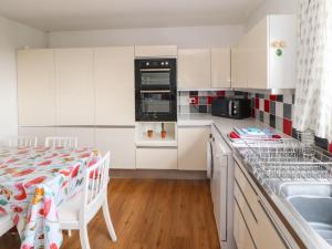 a kitchen with white cabinets and a table and a sink at West Croft in Mawbray