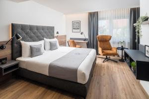 a bedroom with a large bed and a chair at Landhotel Sonne in Neuendettelsau