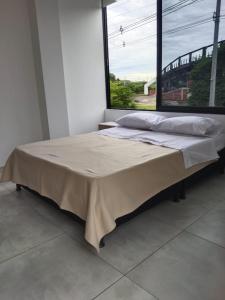 Bett in einem Zimmer mit einem großen Fenster in der Unterkunft Apartamento 302 Yopal in Yopal
