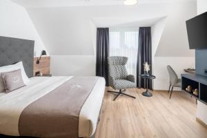 ein Hotelzimmer mit einem großen Bett und einem Stuhl in der Unterkunft Landhotel Sonne in Neuendettelsau