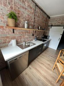 eine Küche mit Spüle und Ziegelwand in der Unterkunft Apartament Stanowisko in Gliwice