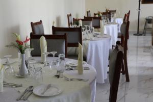 una sala da pranzo con tavoli e sedie bianchi, piatti e tovaglioli di Fatima Hotel a Ruhengeri