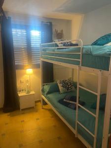 Habitación con 2 literas y lámpara. en Casa Ellenita, en Las Canteras