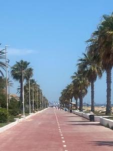 una carretera con palmeras al lado de una playa en Casa Ellenita, en Las Canteras
