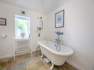 a white bath tub in a bathroom with a window at Ty Het in Llanfairpwllgwyngyll