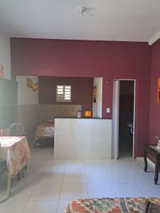 a living room with a red wall and a kitchen at A Toca do Bem-Te-Vi in Águas Belas