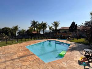 a swimming pool with a patio and palm trees at Pousada Rancho na Represa in Nova Odessa