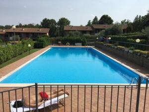 ein großer blauer Pool mit einer Person, die auf einem Stuhl daneben liegt in der Unterkunft Casa BELLA - POOL Garden Parking in Polpenazze del Garda