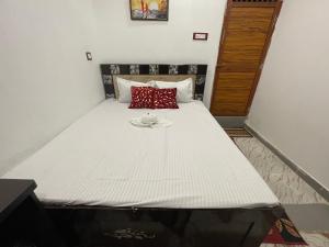 Una cama blanca grande con una almohada roja. en Govind Atithi Grah, en Ayodhya