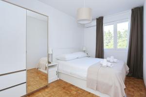 a white bedroom with a bed and a mirror at Apartment Marina in Zadar