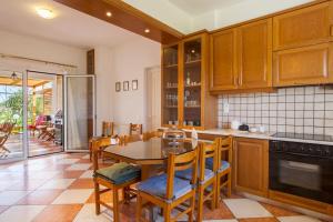 una cocina con armarios de madera, mesa y sillas en Crete's Hidden Treasure - Dream Villa with Pool and Majestic Olive Tree Views en Skalánion