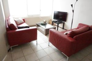 Sala de estar con 2 sillas rojas y TV en Kustverhuur, Oude manege Nieuwvliet, Nieuwvliet 10, en Nieuwvliet