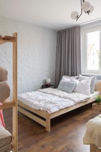 sypialnia z dużym łóżkiem z białymi prześcieradłami w obiekcie Apartament Plaża Zachodnia - 400 m do morza w Kołobrzegu