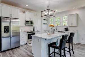 a kitchen with white cabinets and a large island with chairs at Nature's Touch in Edisto Island